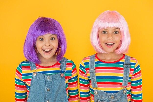 Cheerful friends in bright colorful wigs Anime cosplay party concept Happy childhood concept Anime culture influence Invitation for anime party Happy little girls smiling faces Anime fan