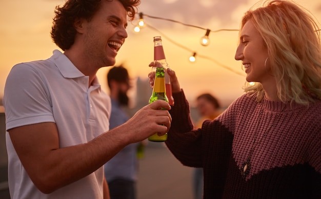 Cheerful friends clinking with drinks during party