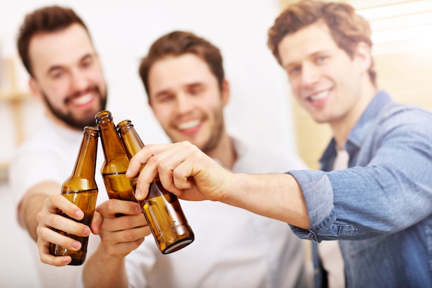 cheerful friends having fun with smartphone and drinking at home