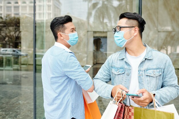 Веселые друзья в медицинских масках приветствуют друг друга локтями во время пандемии