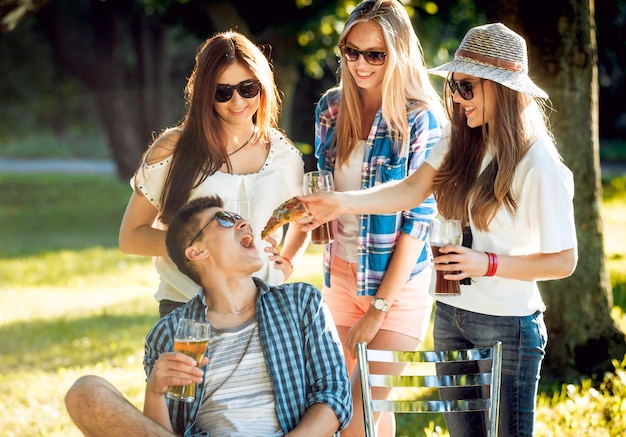 Cheerful friends on picnic in the park. Eating pizza