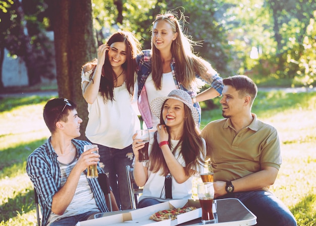 Cheerful friends on picnic in the park. Eating pizza