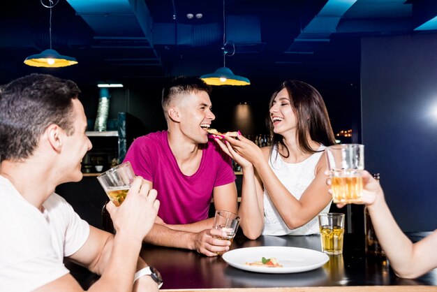 Cheerful friends in the pub. Drinking beer, eating pizza, talking, having fun.