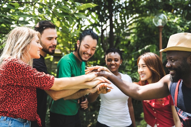 Photo cheerful friends stacking hands at yard