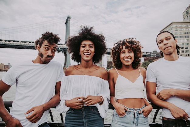 Photo cheerful friends standing against bridge in city