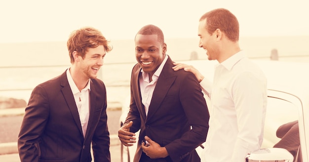 Photo cheerful friends talking while standing next to limousine