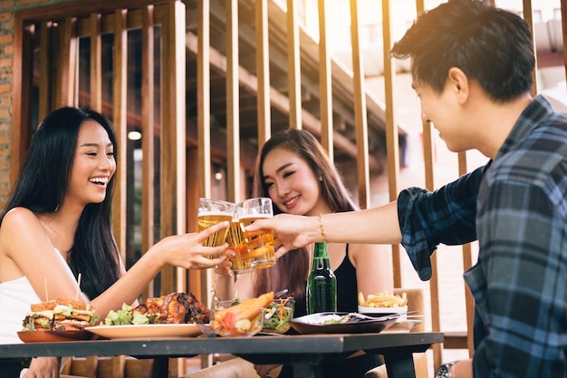 レストランのテーブルでビールグラスを乾杯する陽気な友達