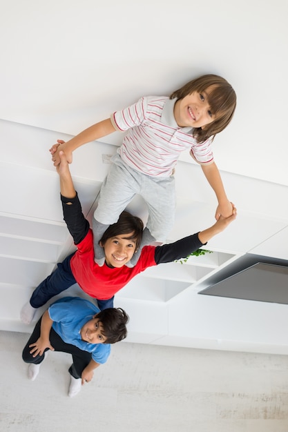 Cheerful funny children having fun and posing line up piggyback in new modern home