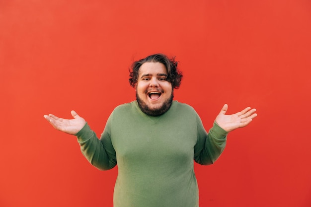 Cheerful and funny fat young hispanic man is expressing a confusion by a gesture throwing up