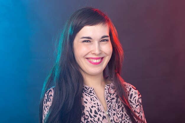 Cheerful funny young brunette woman with long hair posing on colorful background