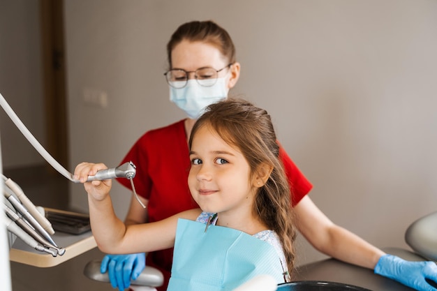 Cheerful girl child holding stomatology tools and smile in dentistry The child smiles at the consultation with the dentist