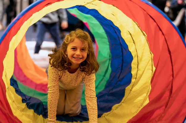 Cheerful girl in colorful tube in playroom