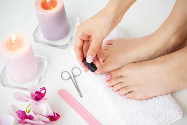 Photo cheerful girl doing nails making pedicure sitting in bed indoor