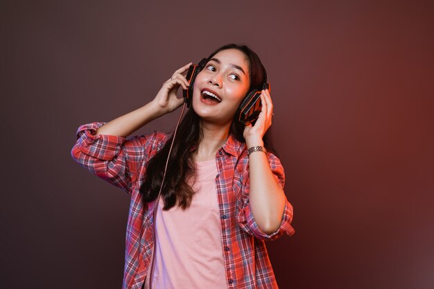 Cheerful girl enjoying music using headphones with two hands holding headphones