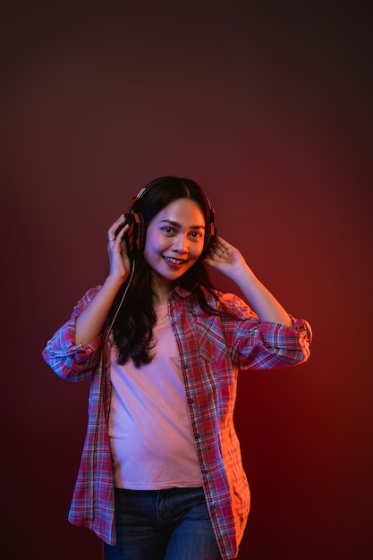 Cheerful girl enjoying music using headphones with two hands holding headphones