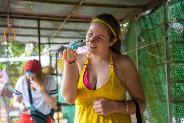 Cheerful girl feeds the parrots from her hands and laughs contact zoo