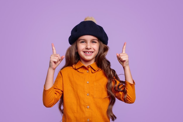 Cheerful girl in hat pointing up