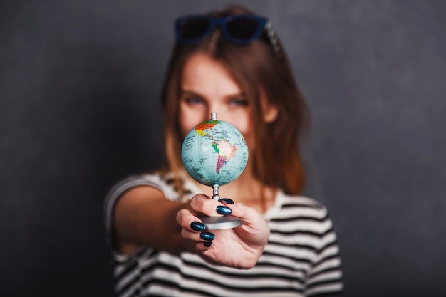 Foto ragazza allegra che tiene il biglietto aereo del passaporto e il globo prima del concetto di viaggio interno su sfondo grigio