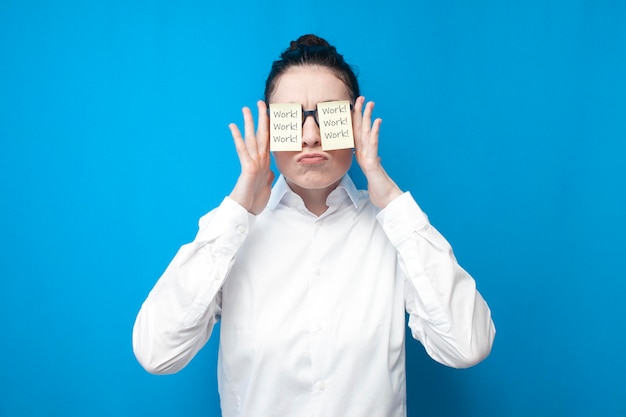 cheerful girl manager in white shirt with blank papers in front of her eyes smiles