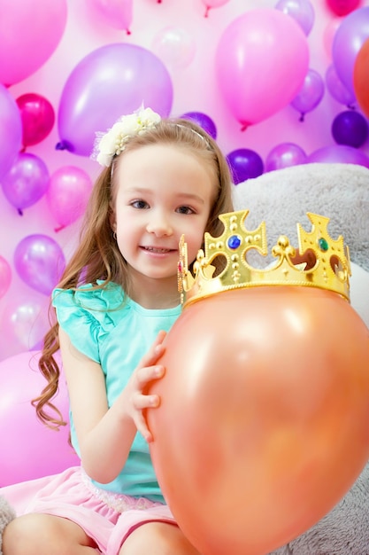 Photo cheerful girl playfully put crown on balloon