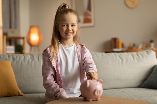 Piggybank にお金を入れて陽気な女の子屋内での個人的な貯蓄を上げる