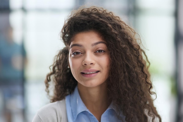 Cheerful girl standing at modern office looking at camera