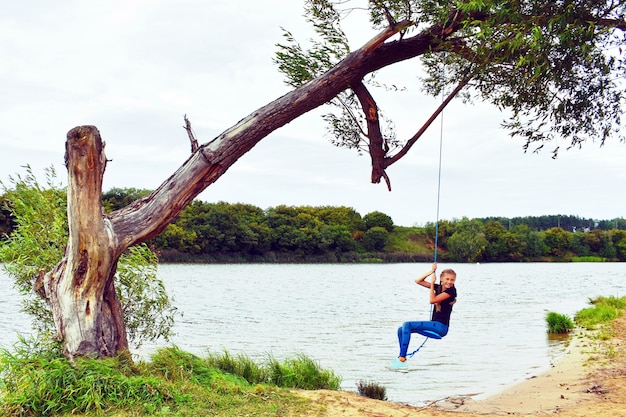 Cheerful girl swinging on a rope swing