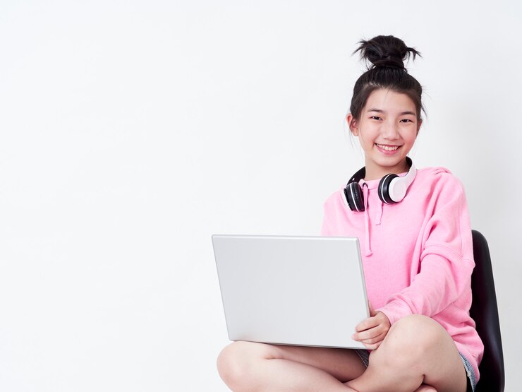 椅子に座ってラップトップを使用して陽気な女の子。