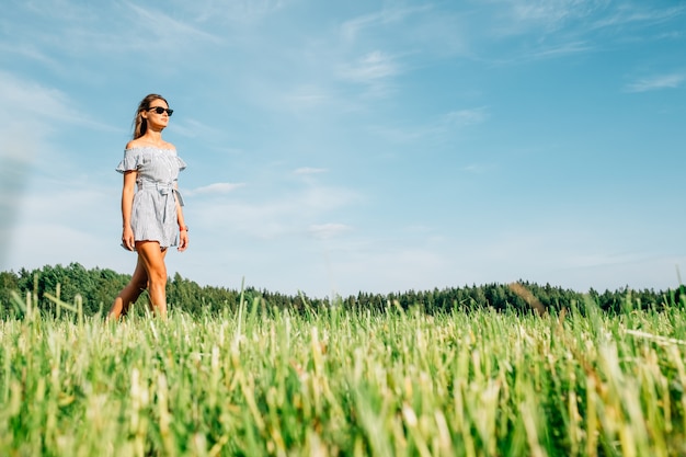 Cheerful girl walks outside in a meadow