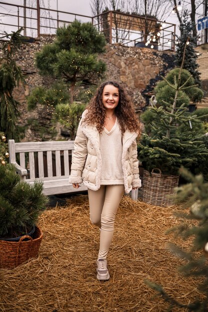 A cheerful girl walks among the trees and smiles, she has a New Year's mood