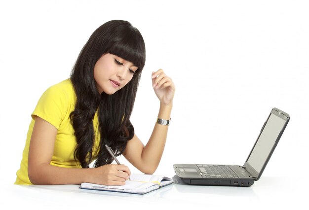 Cheerful girl with laptop and write on a books, isolated 