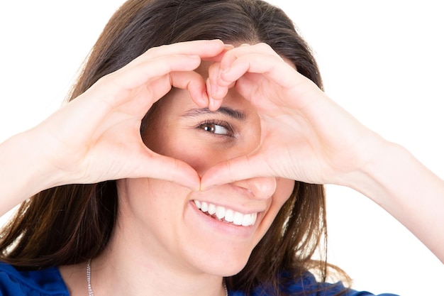 Foto ragazza allegra con i capelli lunghi che fanno a forma di cuore con le dita con l'occhio marrone