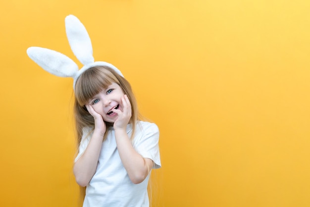 黄色の背景に彼女の頭にウサギの耳を持つ陽気な女の子面白いクレイジー幸せな子供イースターの子供イースター休暇のプロモーションアイテムの準備テキストモックアップのスペースをコピー