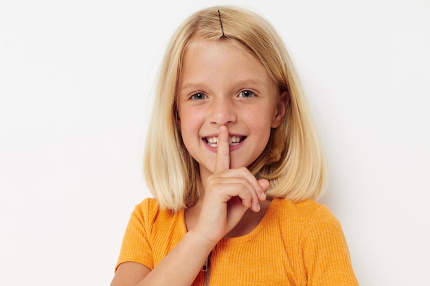 Cheerful girl in a yellow tshirt posing light background