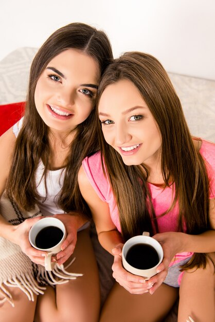 Cheerful girls in pajamas with coffee