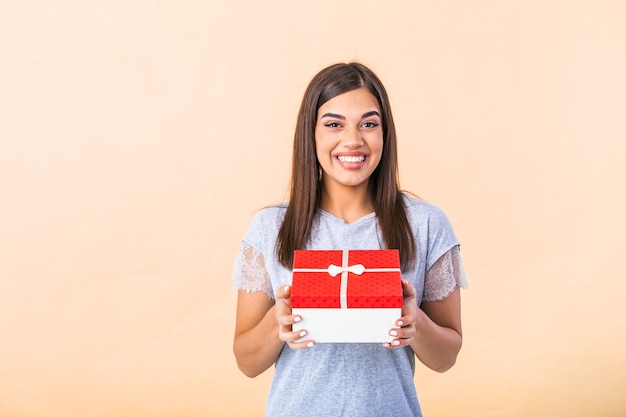 Cheerful good looking young woman holding a red Christmas gift box in her hands