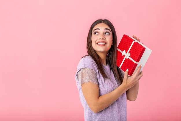 Cheerful good looking young woman holding a red Christmas gift box in her hands