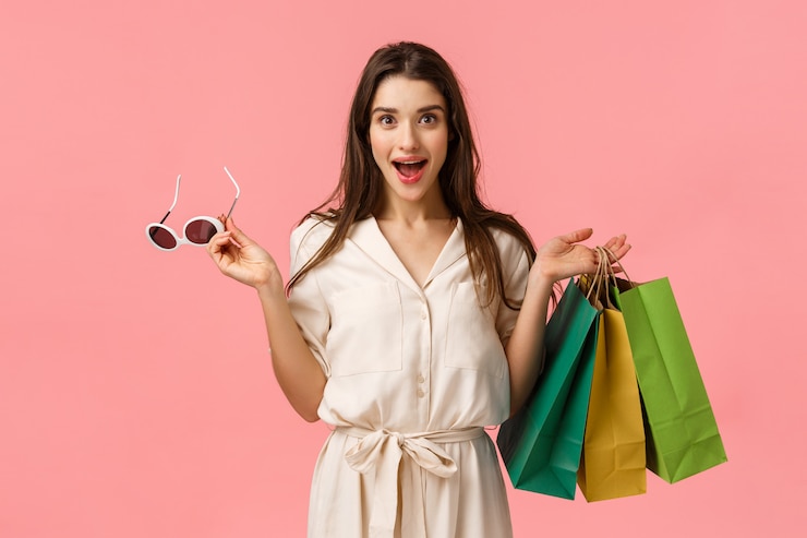 Photo cheerful gorgeous caucasian woman in dress, holding shopping bags and sunglasses