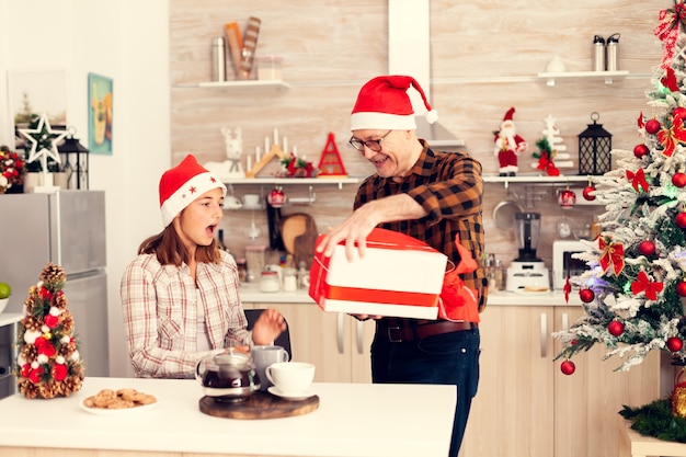 素敵なギフトボックスを与えるクリスマスを祝う陽気なおじいちゃん