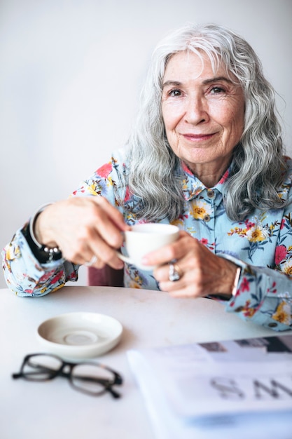 Веселая бабушка пьет кофе в кафе