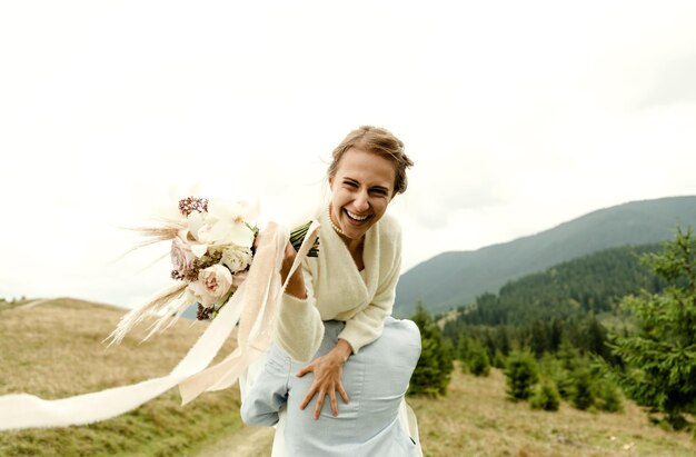 Cheerful groom holds a beautiful bride in his arms happy young couple playing and indulging on wedding day