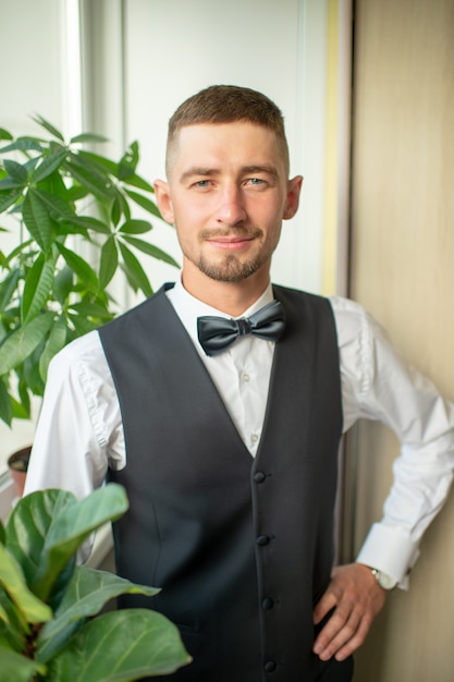 cheerful groom in suit and bowtie indoor portrait