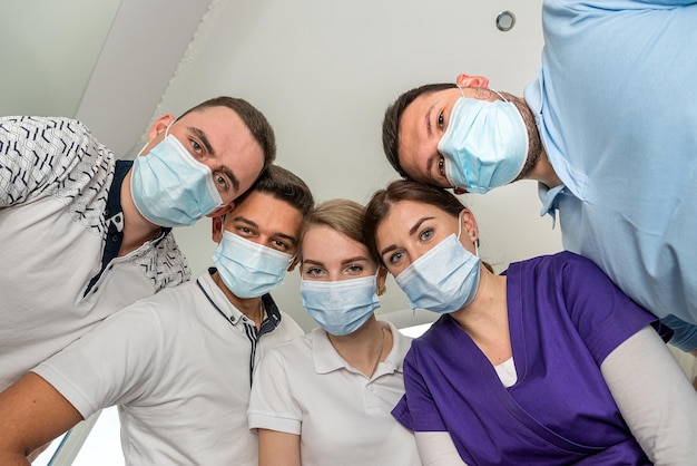 A cheerful group of dentists and their assistants stand in the dental office and smile happily