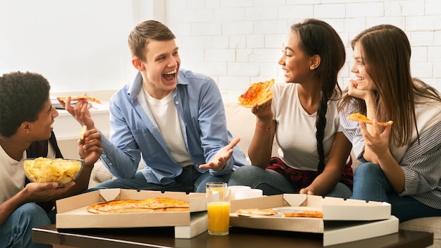 Photo a cheerful group of four young friends is gathered in a comfortable living room enjoying slices of