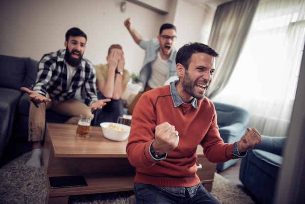Photo cheerful group of friends watching football game on tv