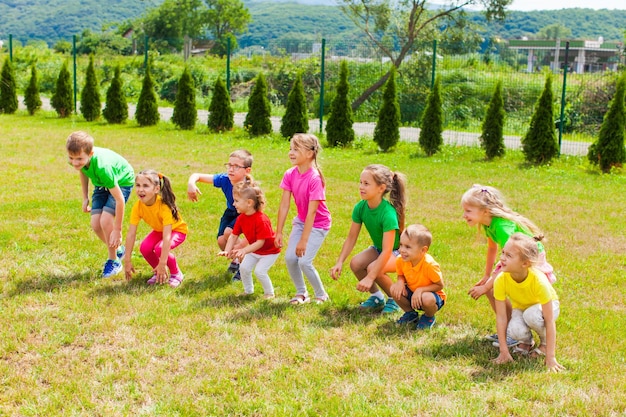 Foto il gruppo allegro di bambini si diverte sull'erba. giochi all'aperto