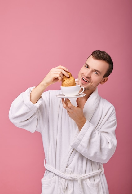 Cheerful guy can't resist lest he eat croissant