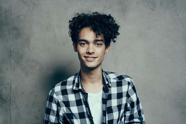 Cheerful guy curly hair and plaid shirt modern style studio model