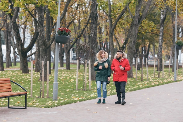 쾌활한 남자와 여자가 가을 공원에서 걷고있다