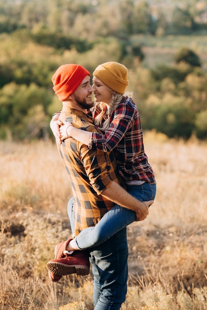 Cheerful guy and girl on a walk in bright knitted hats and plaid shirts